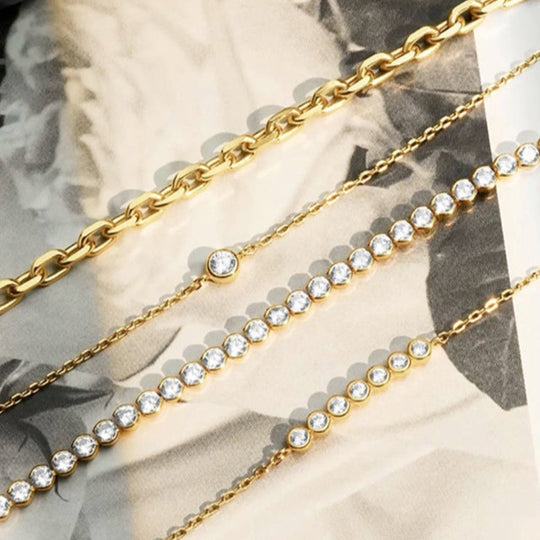 Four  Ania Haie gold bracelets on a black and white background